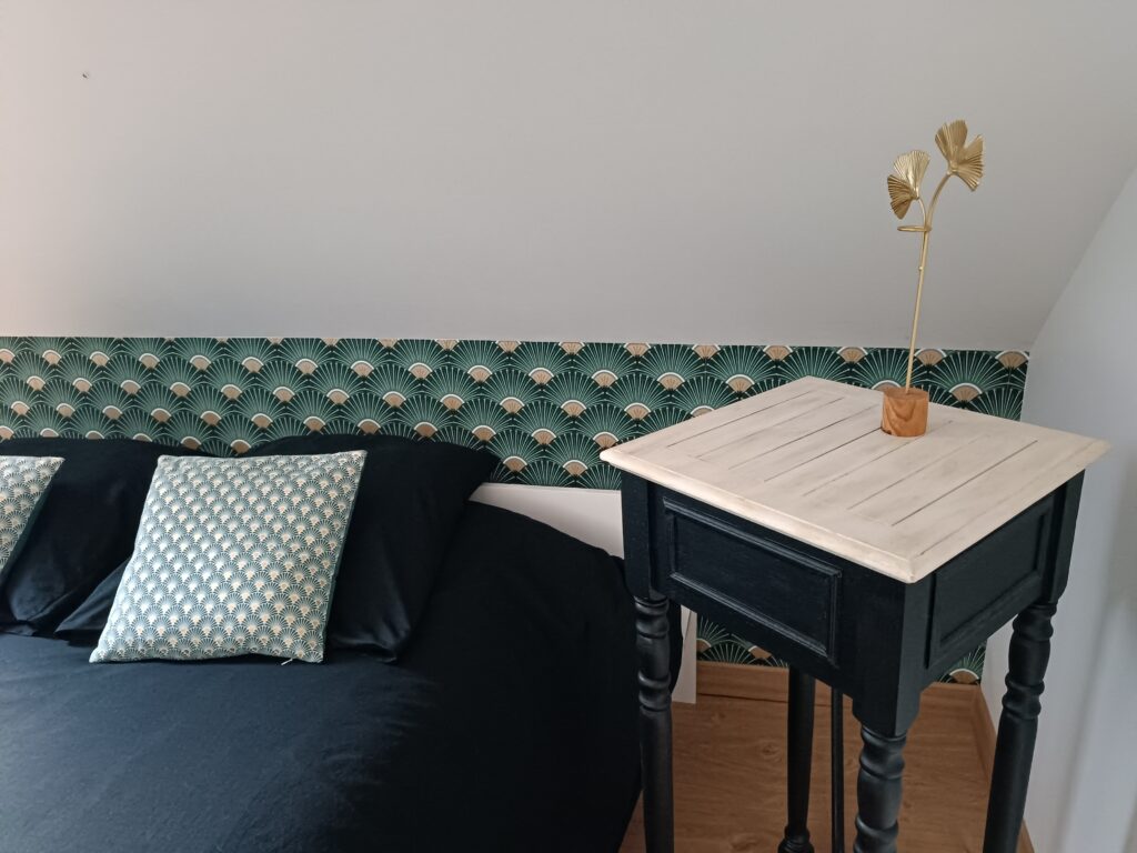 Détail de la décoration de la chambre La Balade avec papier peint Art déco, mobilier noir et touches dorées