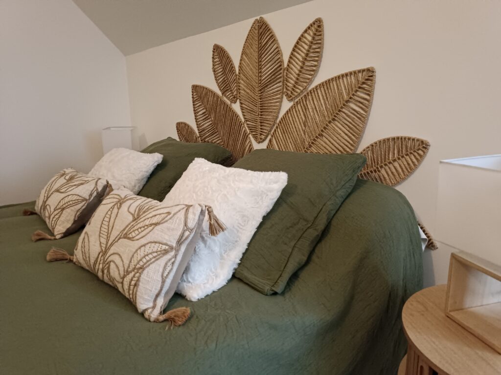 Tête de lit en fibres naturelles et coussins vert sauge de la chambre La Bohème