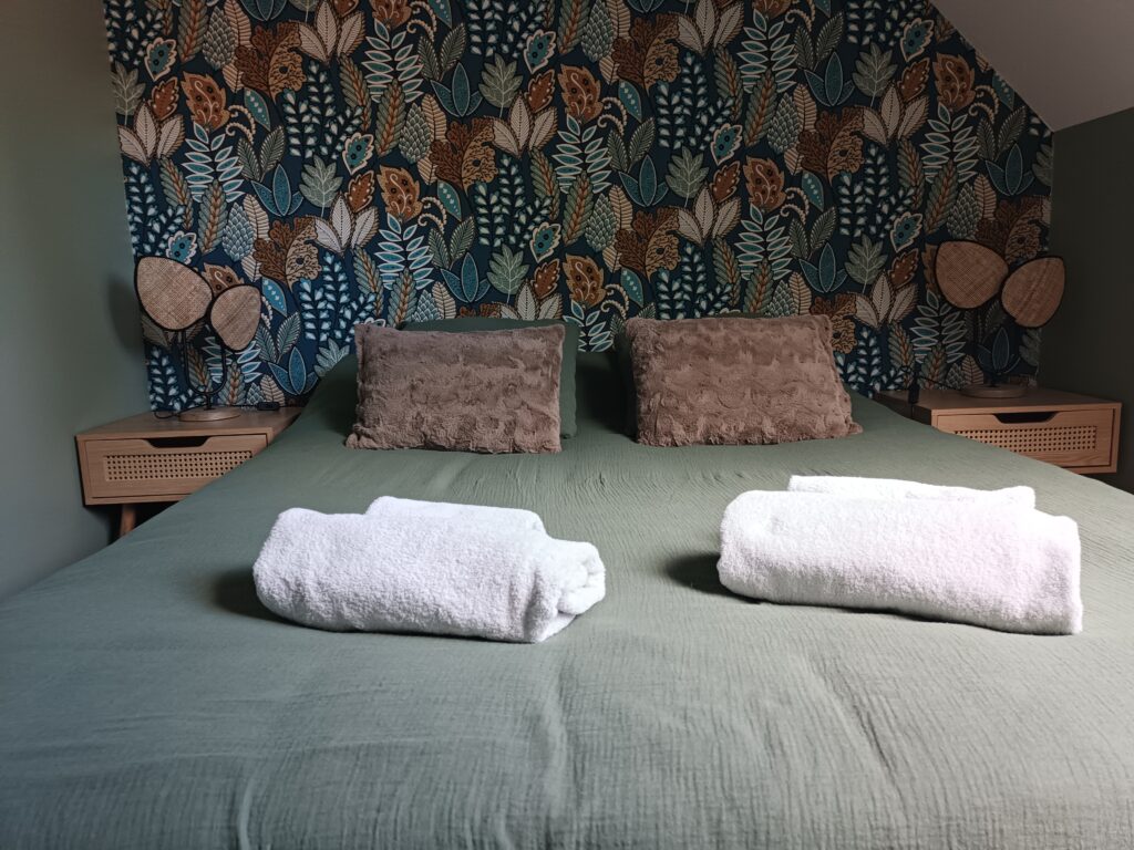 Lit double de La Vintage avec linge de toilette et papier peint végétal