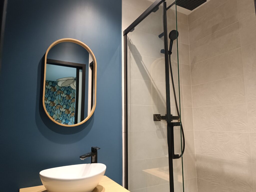 Douche et miroir de la salle d’eau de La Vintage avec reflet de la décoration de la chambre